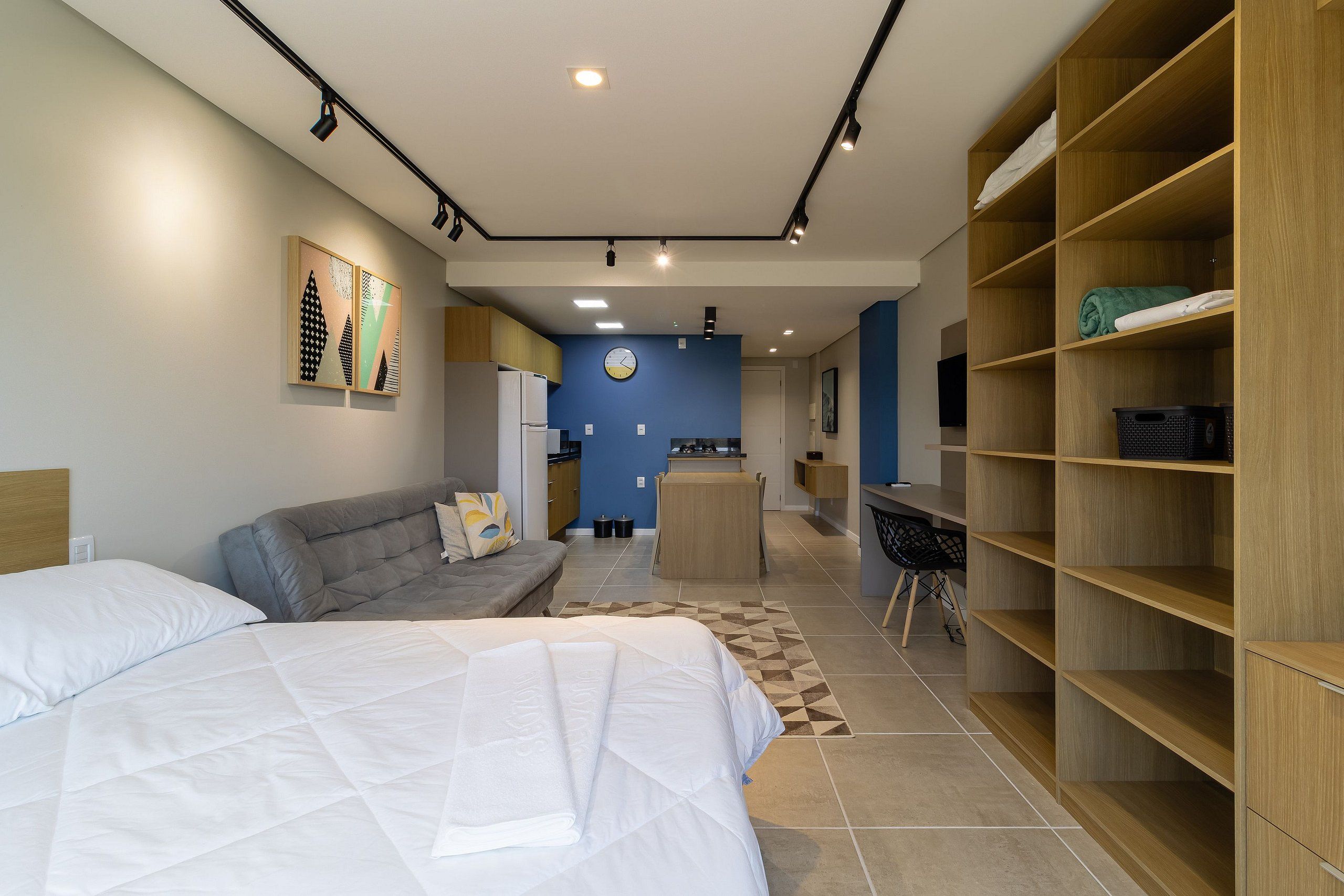 A modern hotel room with a bed, a sofa, a desk, and a wardrobe.