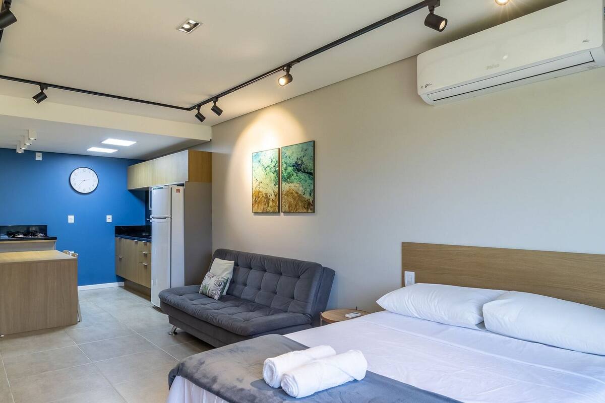 Une chambre d’hôtel moderne équipée d’un lit, d’un canapé, d’un petit coin cuisine et d’un appareil de climatisation.