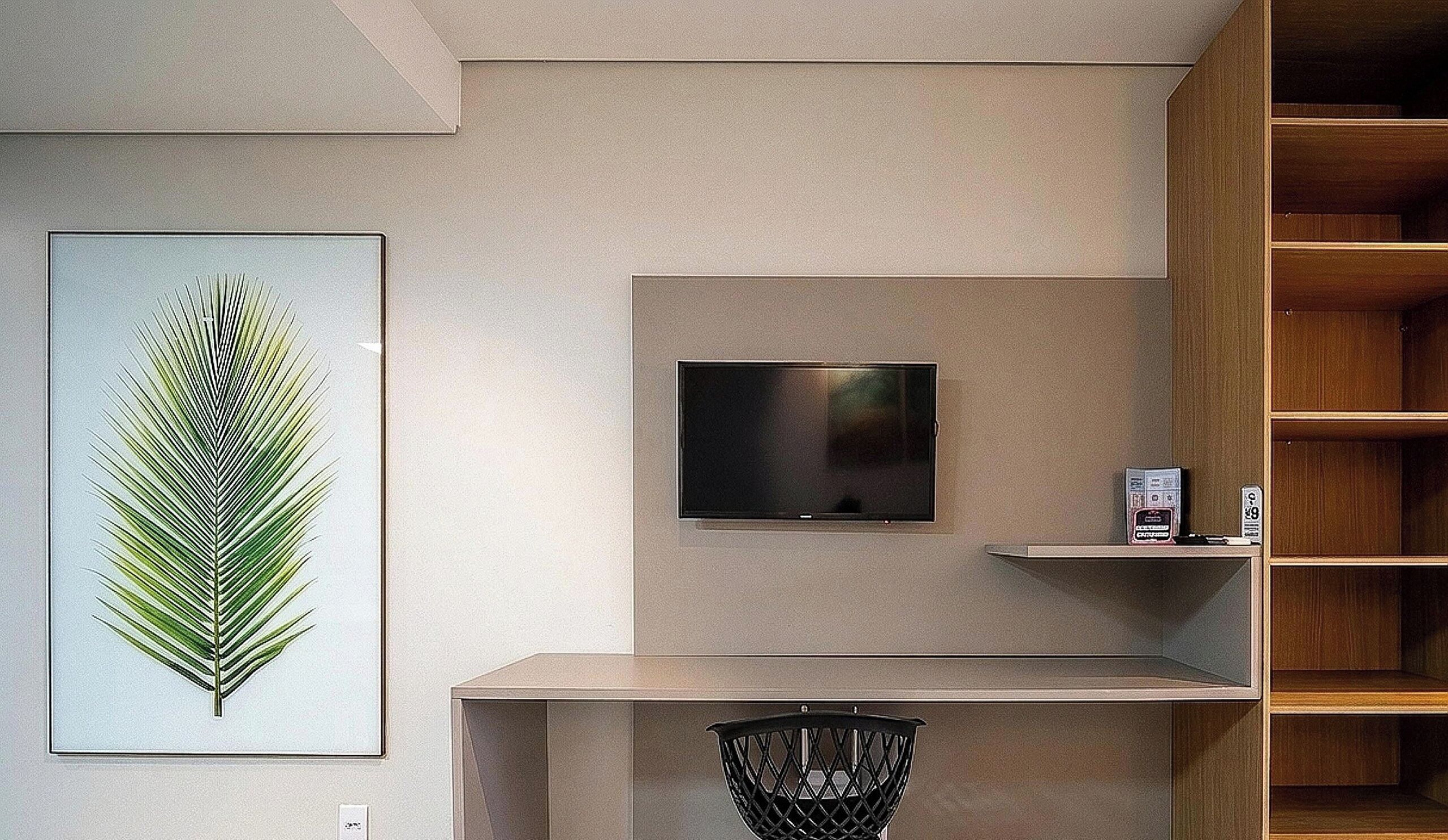 Un interior modern amb un televisor penjat, una planta emmarcada i una estant de fusta.