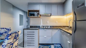 Una cucina moderna con mobili grigi, un frigorifero in acciaio inossidabile e un forno a microonde.