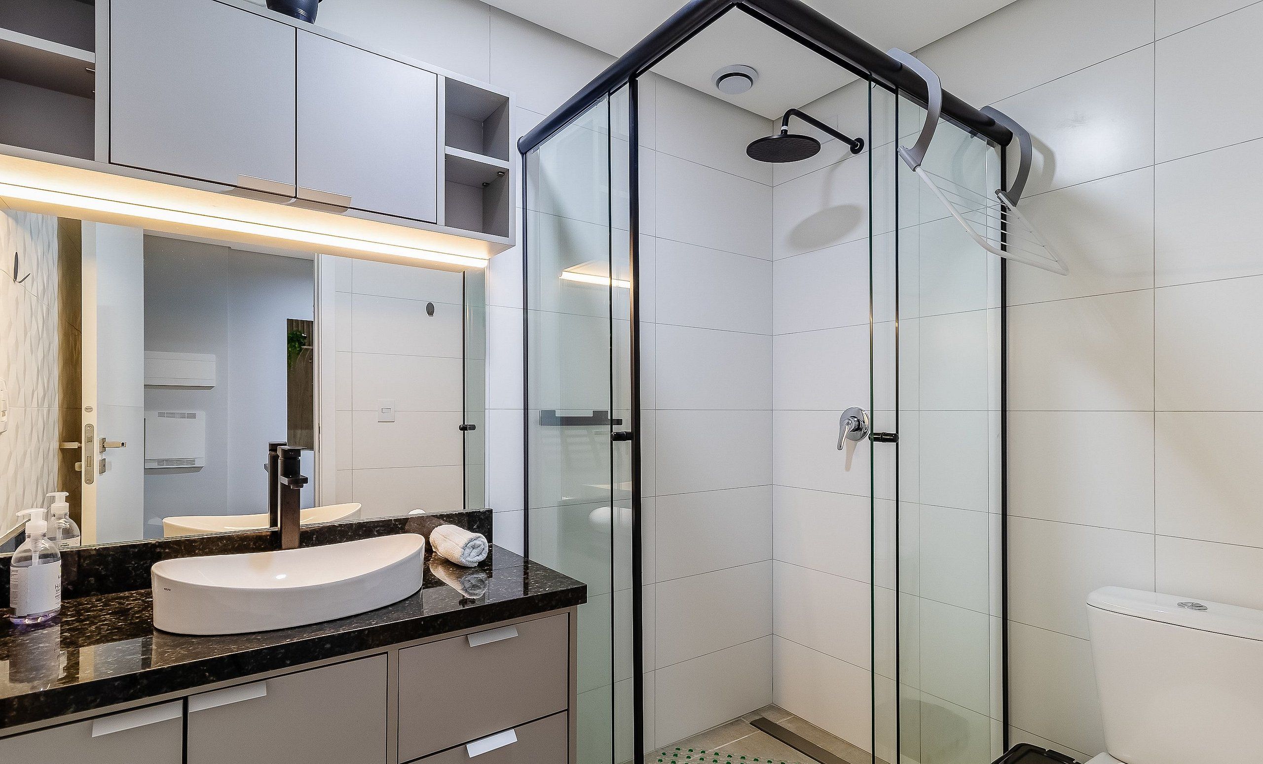 A modern bathroom with a glass-enclosed shower, a vanity with a curved sink, and a large mirror.