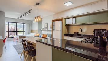 Una cocina moderna con una isla central, un comedor con sillas y un amplio ventanal con vistas al exterior.