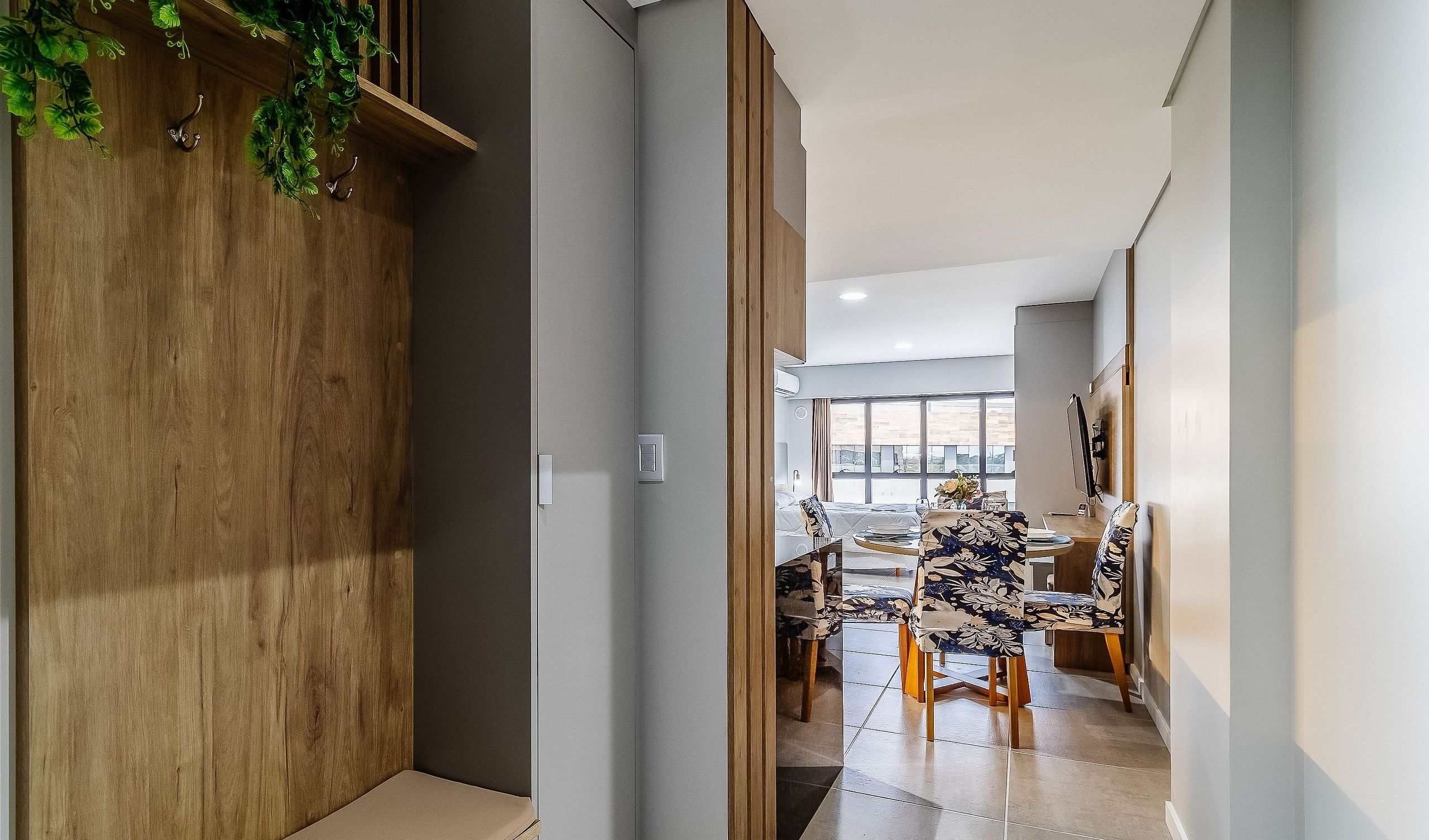 A modern interior with a dining area, wooden accents, and a view through a doorway.