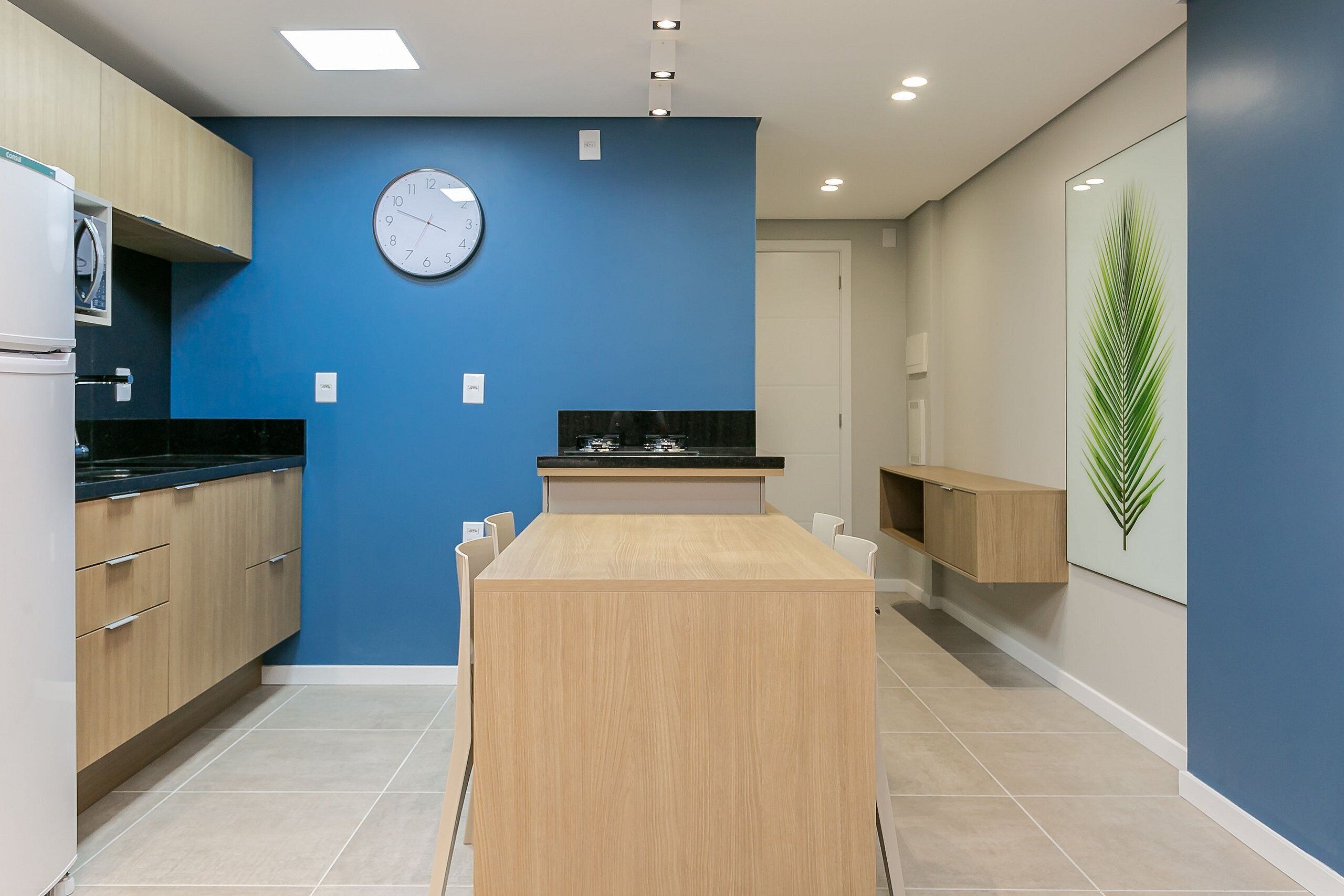 Una cocina moderna con una isla central, armarios de madera, un reloj y una planta decorativa.