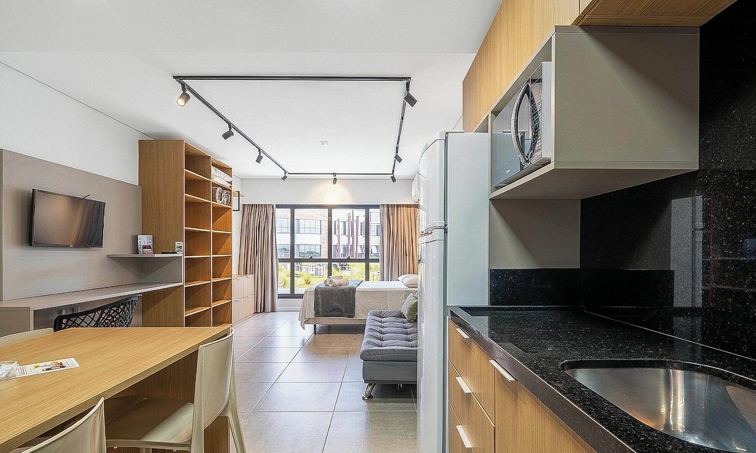 A compact kitchen with a built-in oven, a dining area with a table and chairs, and a seating area with a sofa.
