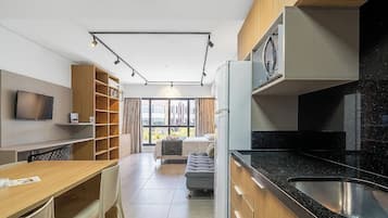 A compact kitchen with a built-in oven, a dining area with a table and chairs, and a seating area with a sofa.