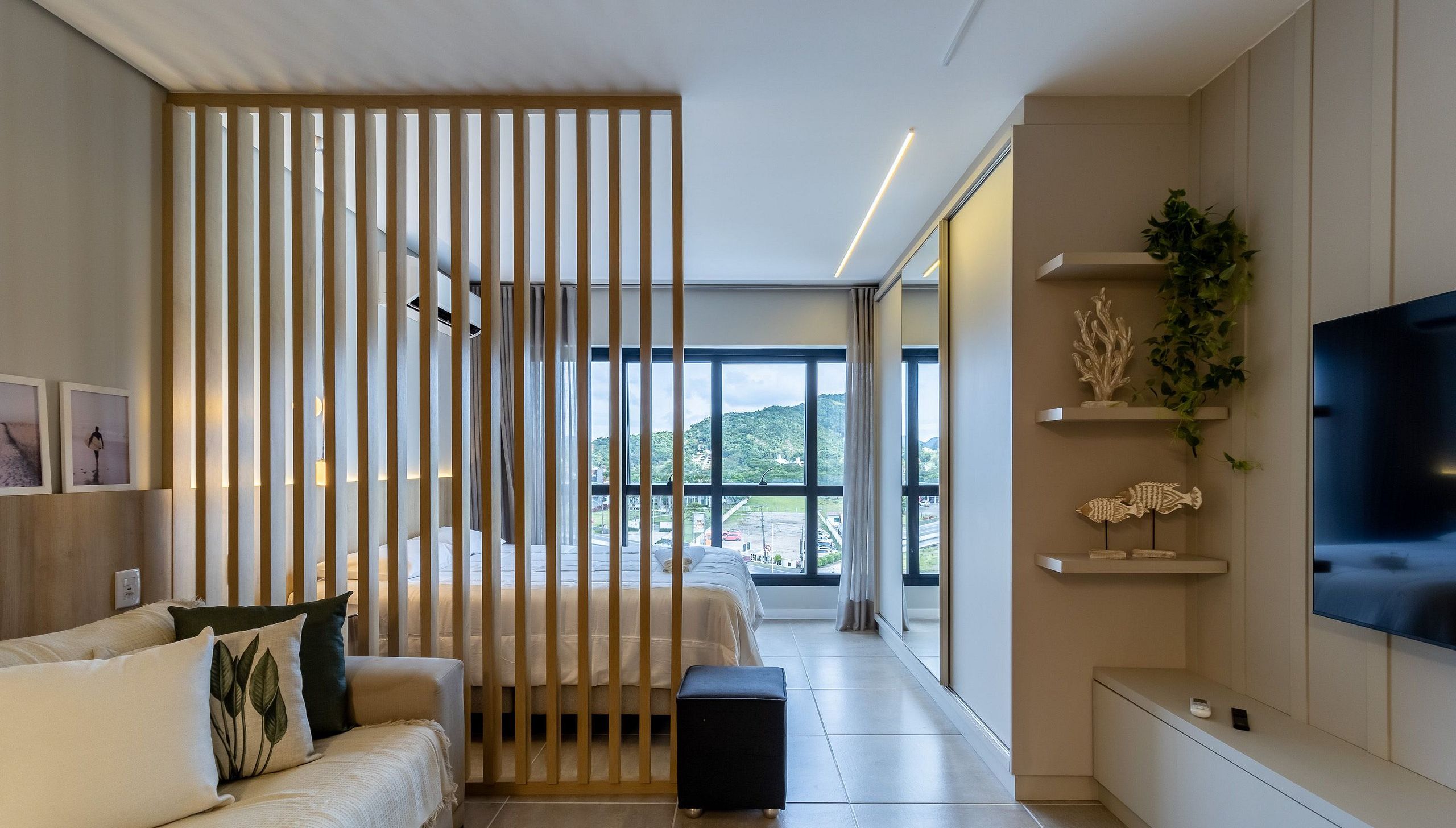 Une chambre d’hôtel moderne équipée d’un lit, d’un canapé, d’une télévision et offrant une vue sur l’extérieur.