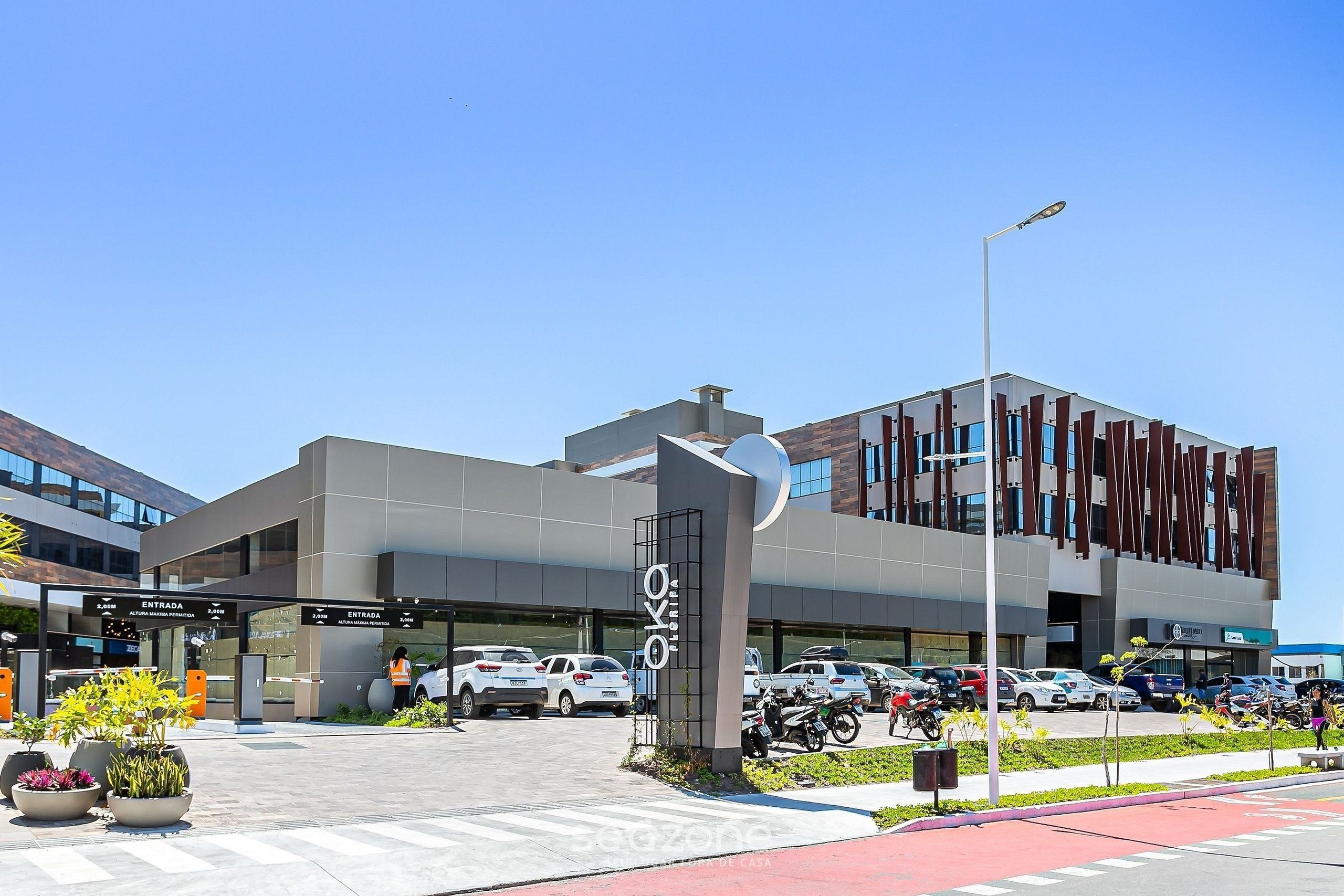 A modern building with a parking lot, a clear sky, and a street with a red bike lane.