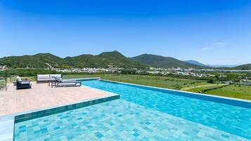 A swimming pool with lounge chairs and a view of a town and mountains.