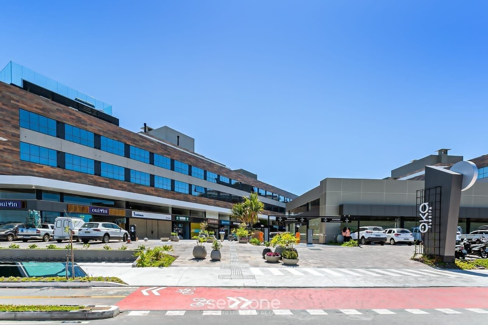 A modern building with multiple floors, a parking area, and a clear sky.
