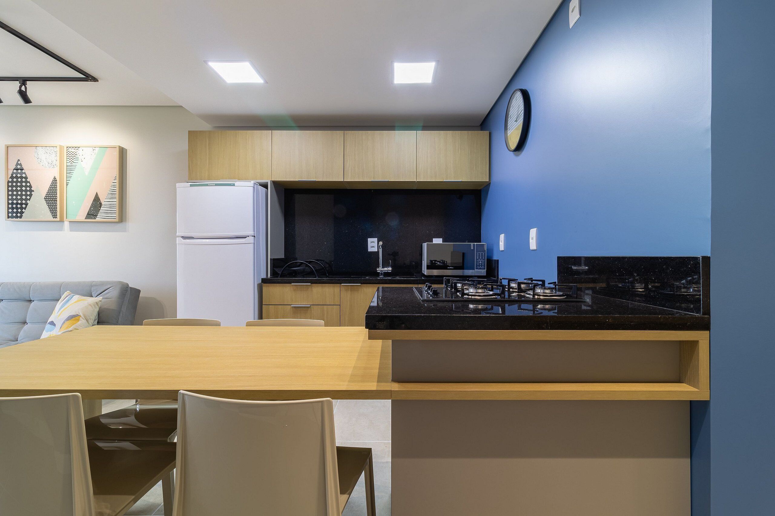A modern kitchen with a refrigerator, microwave, stove, and dining area with chairs and a table.