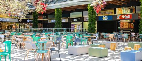 Un espace café en plein air avec différents types d’aménagement, comprenant des tables et des chaises, et un motif décoratif sur le sol.