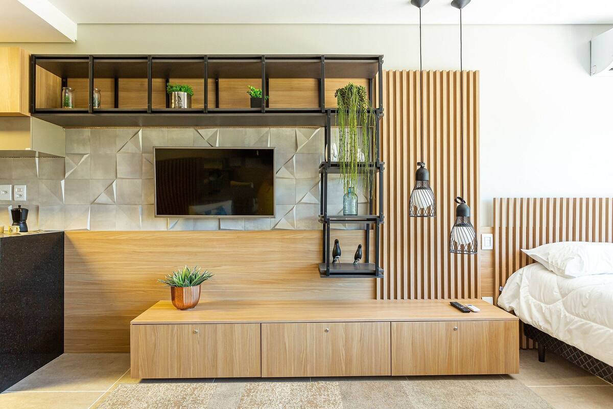 Un salon moderne avec un téléviseur, des meubles en bois et une plante posée sur la console.