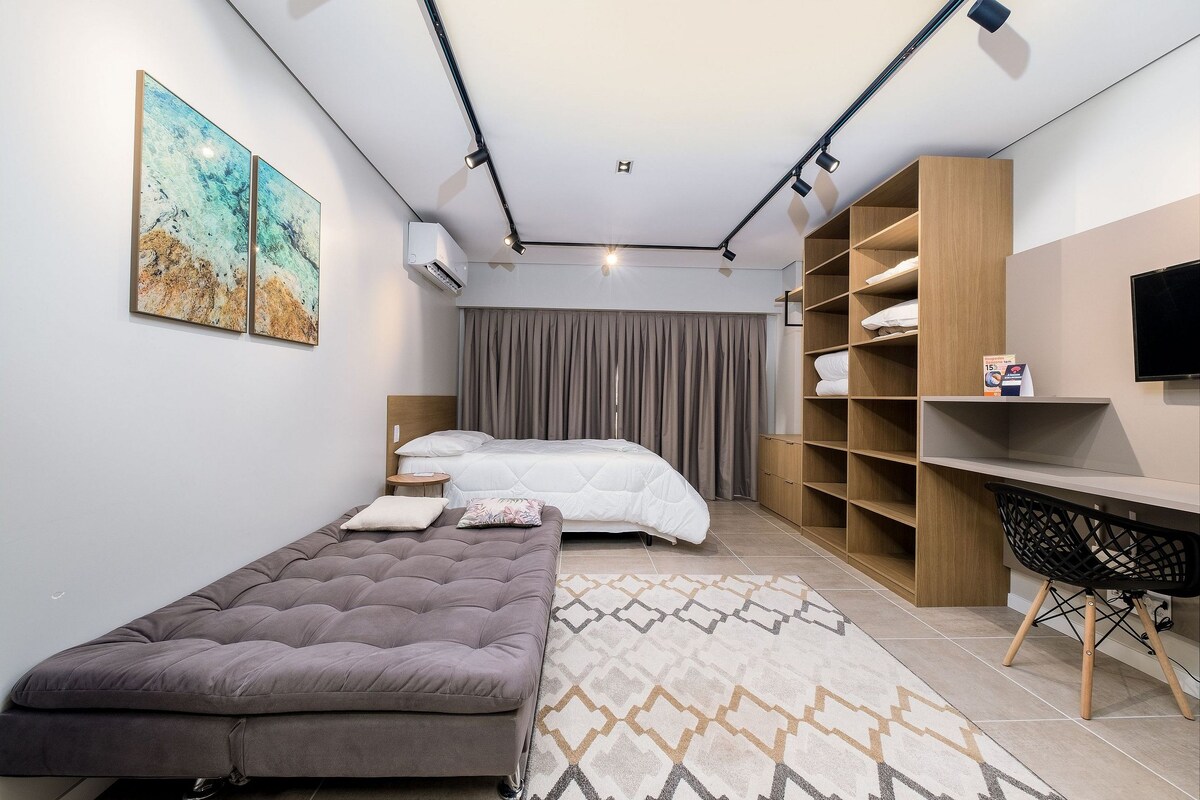 Een moderne slaapkamer met een bed, een bank, een bureau en een televisie.