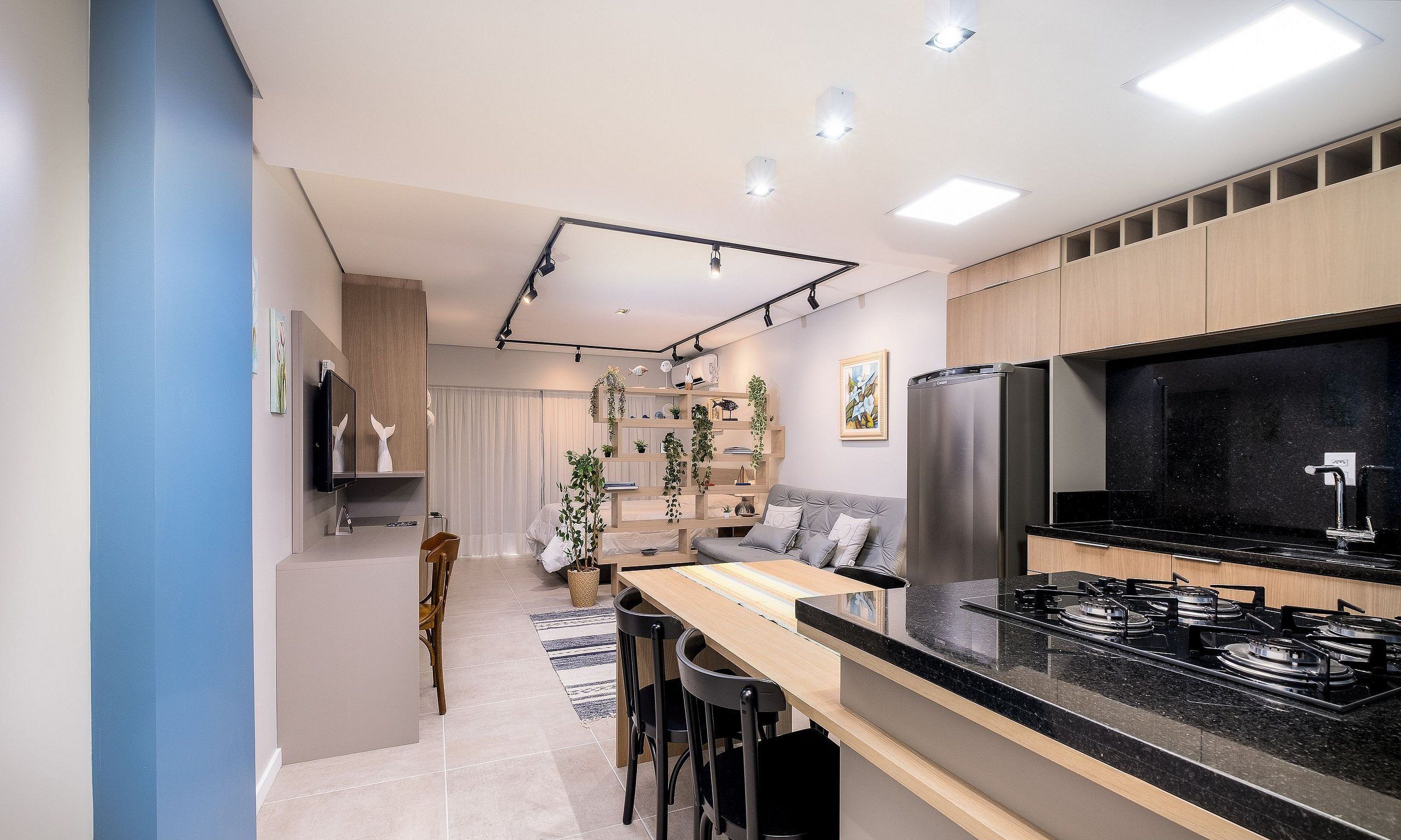 A modern kitchen with a black countertop, stainless steel appliances, and a dining area with a wooden table and chairs.