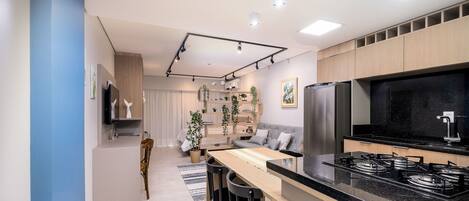 A modern kitchen with a black countertop, stainless steel appliances, and a dining area with a wooden table and chairs.