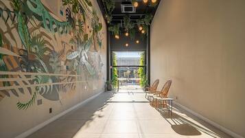 A corridor with a mural, a seating area, and a view through a glass door.