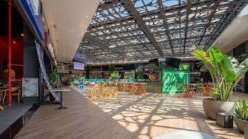 Un atrio interior con techo alto, vigas metálicas con diseño y plantas en macetas.