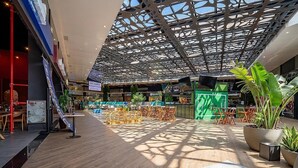 An indoor atrium with a high ceiling, patterned metal beams, and potted plants. - OKA Floripa (Florianópolis)