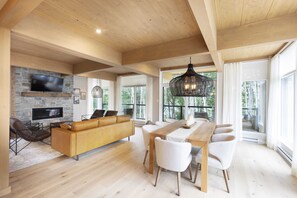 Un salón amplio con techo de madera, pared de piedra y ventanas grandes.