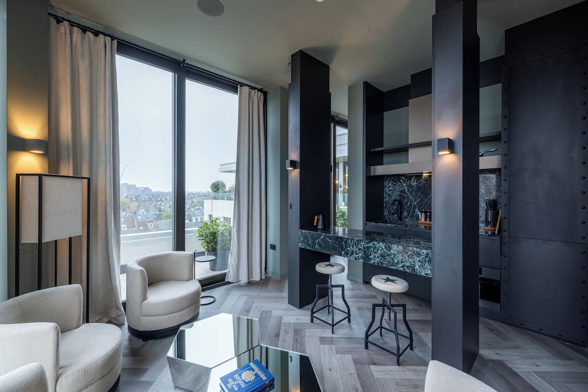 A modern living room with a large window, a sofa, a coffee table, and a kitchen area with a marble countertop.