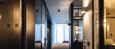 Une chambre d’hôtel moderne avec un plancher en bois, un lit, un bureau et une salle de bain équipée de toilettes et d’un lavabo.