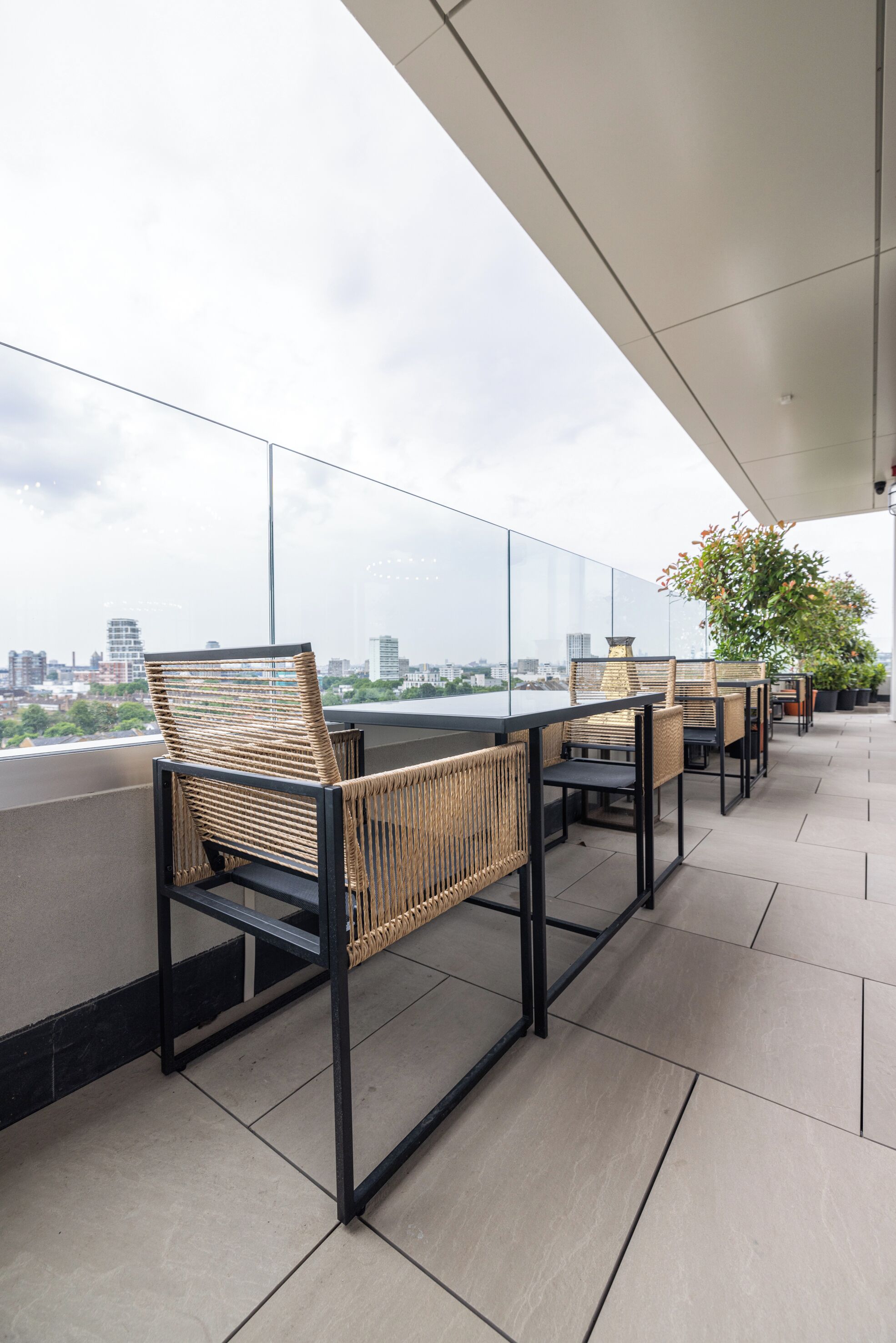 Terraza en la azotea con sillas y mesas de mimbre, con vistas a la ciudad.