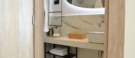 A modern bathroom with a marble backsplash, a white sink, and a mirror above the countertop.