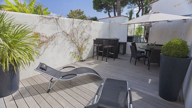 An outdoor patio with a dining table and chairs, a lounge chair, and a large potted plant. - Maison Verte 4 Pers (LA FLOTTE)