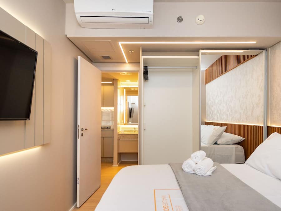 Una habitación de hotel con una cama, un televisor, un baño y un pasillo que conduce a otra habitación.