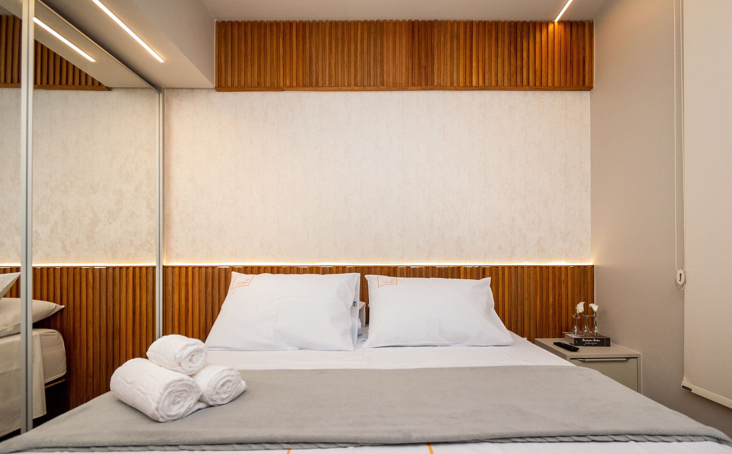 Une chambre d’hôtel avec un lit, une table de chevet et un miroir.