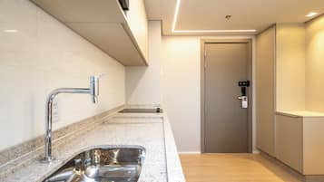 A modern kitchen with a stainless steel sink, a built-in oven, and a microwave.