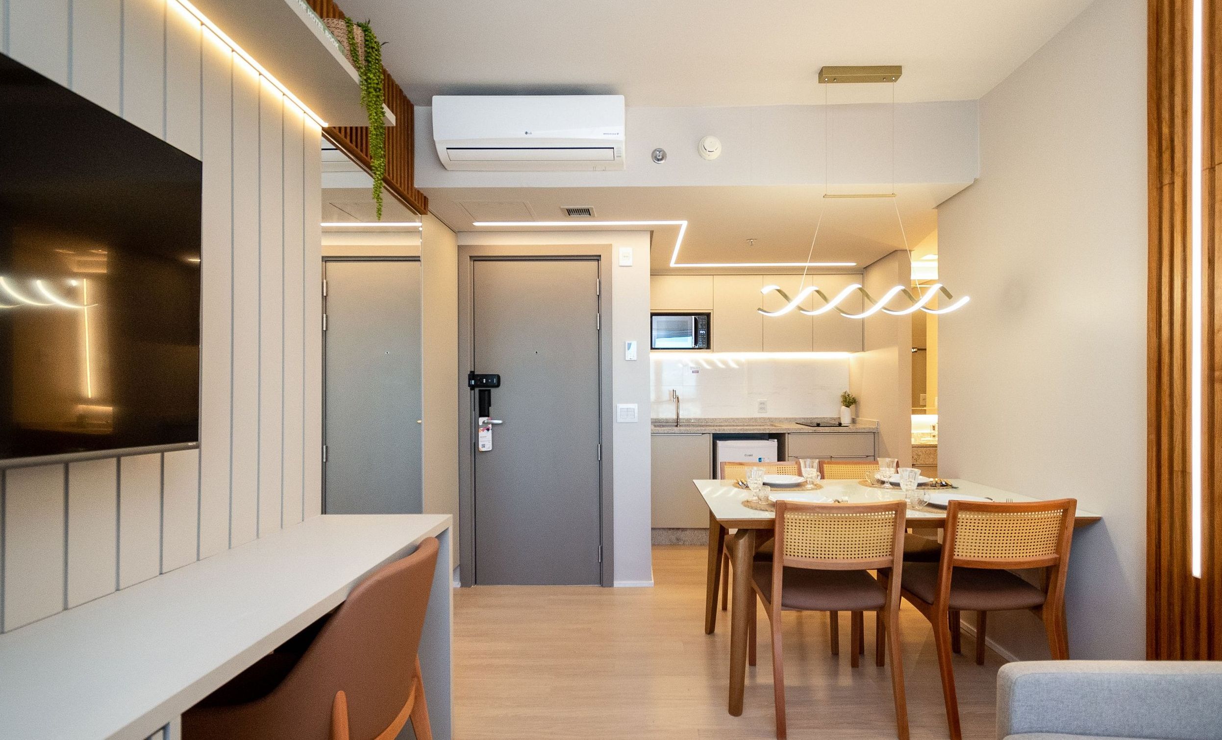 A modern kitchen with a microwave, a dining table set for four, and a staircase leading to an upper level.