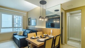 Uma área de refeições moderna com uma mesa de madeira posta para quatro pessoas, um sofá e luminárias pendentes.