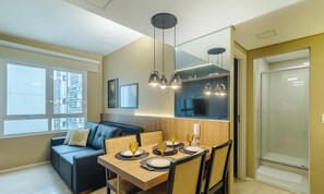 Un espace repas moderne avec une table en bois dressée pour quatre personnes, un canapé et des luminaires suspendus.
