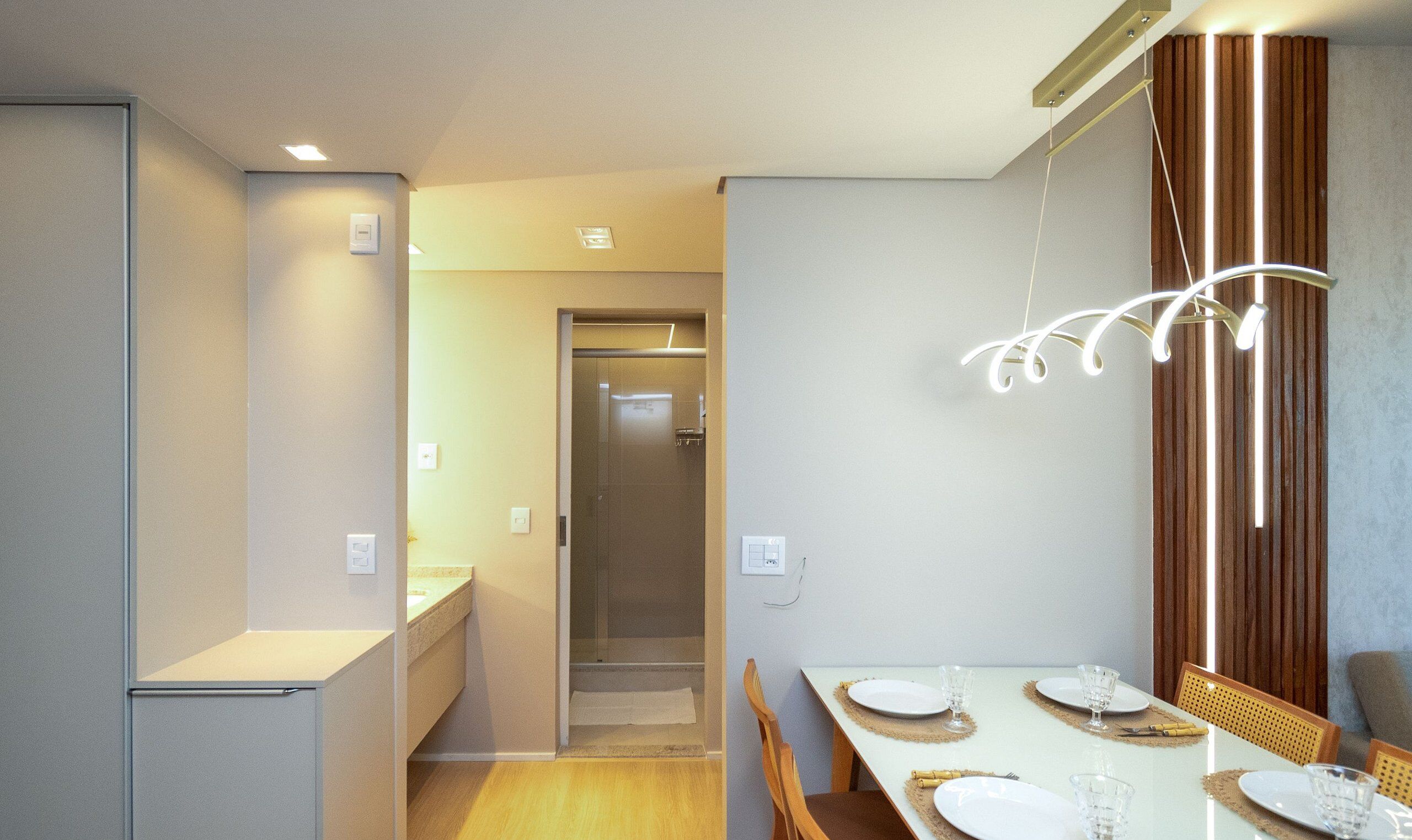 A modern dining area with a long table, chairs, and a unique light fixture.