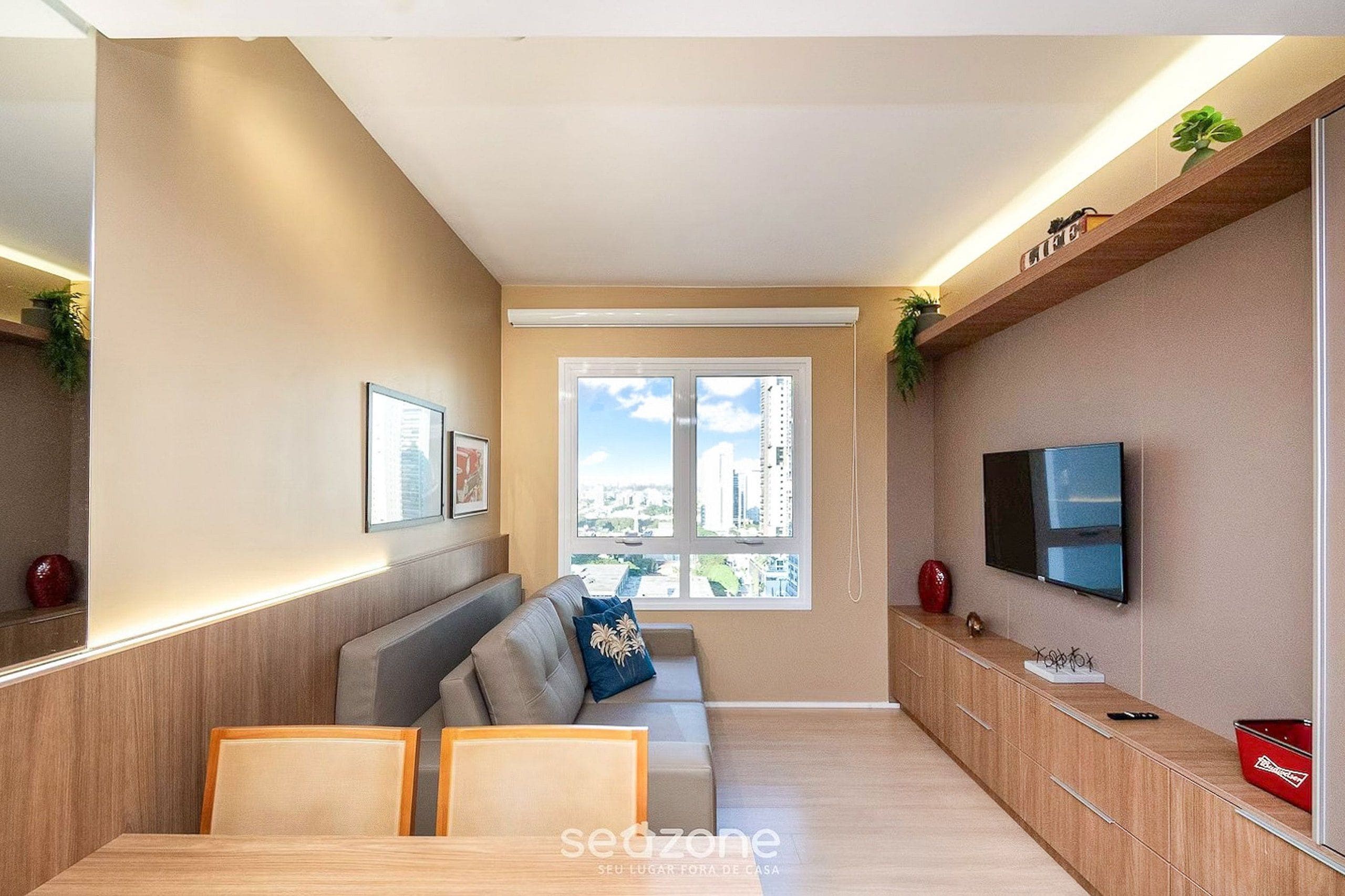 A modern living room with a sofa, TV, and a window with a city view.