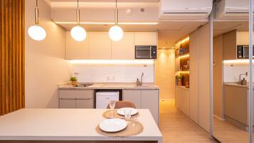 Cozinha moderna com área de refeições, armários brancos e iluminação pendente.