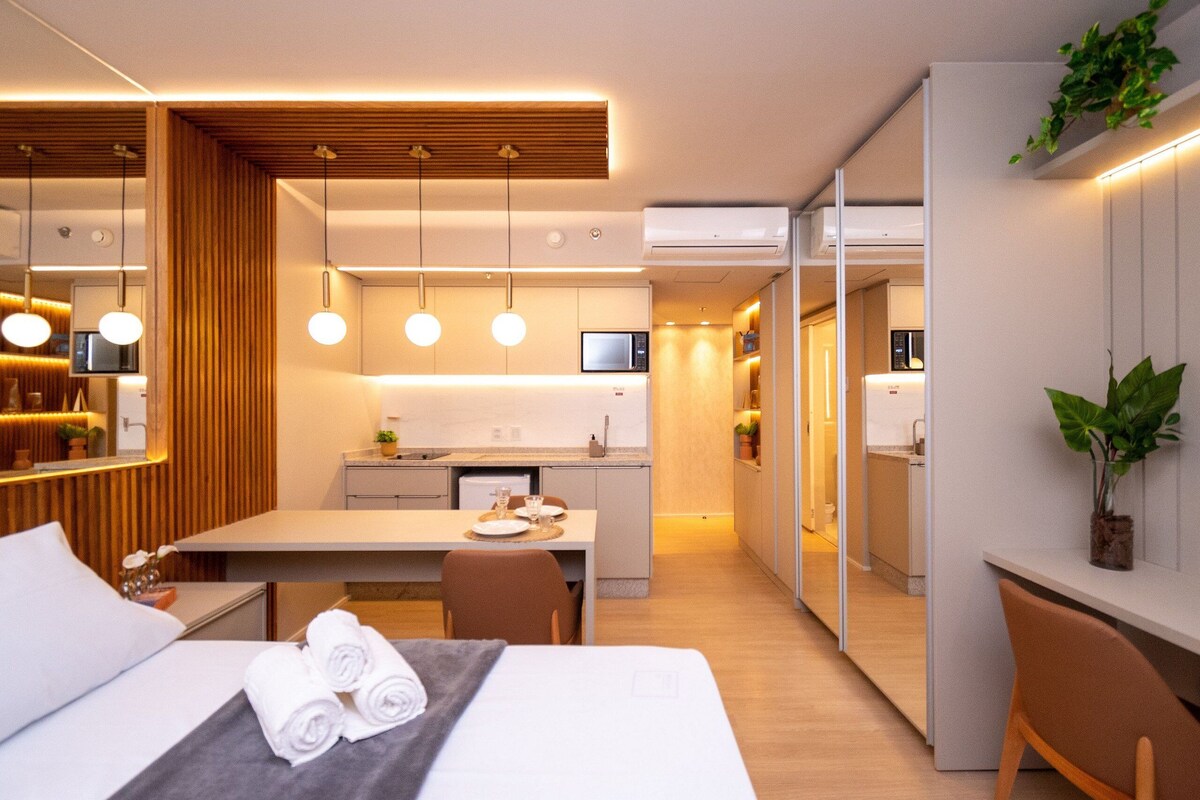 Une chambre d’hôtel moderne équipée d’un lit, d’un bureau, d’un coin repas et d’une kitchenette.