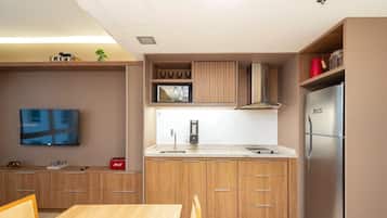 A compact kitchen with wooden cabinets, a stainless steel refrigerator, a microwave, and a coffee maker.