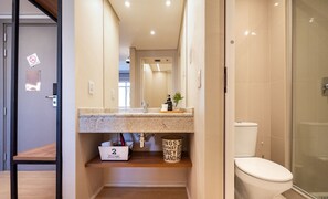 Une salle de bain moderne équipée d’une douche, de toilettes et d’un meuble-lavabo avec un miroir.