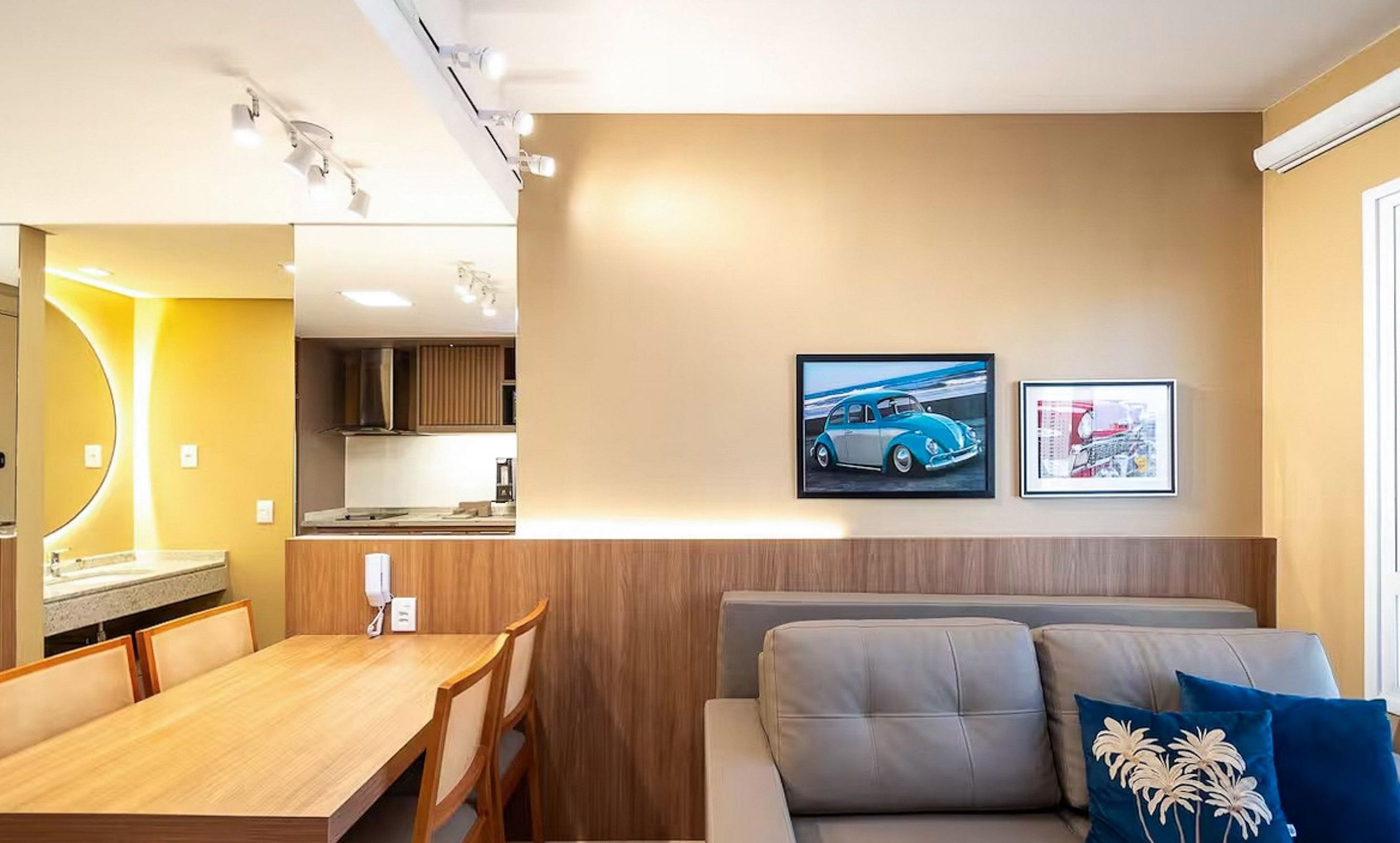 A modern interior with a wooden dining table, a sofa, and a kitchenette.