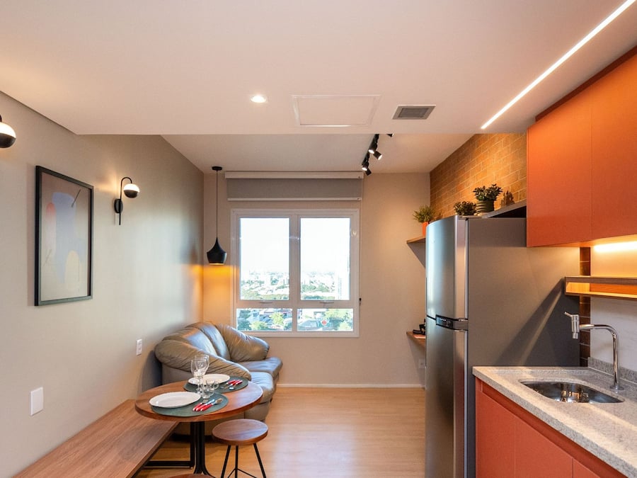 A compact kitchen with a built-in refrigerator, a dining area with a table and chairs, and a window providing natural light.