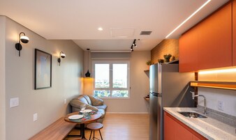 Una cocina compacta con refrigerador integrado, un comedor con mesa y sillas, y una ventana que proporciona luz natural.
