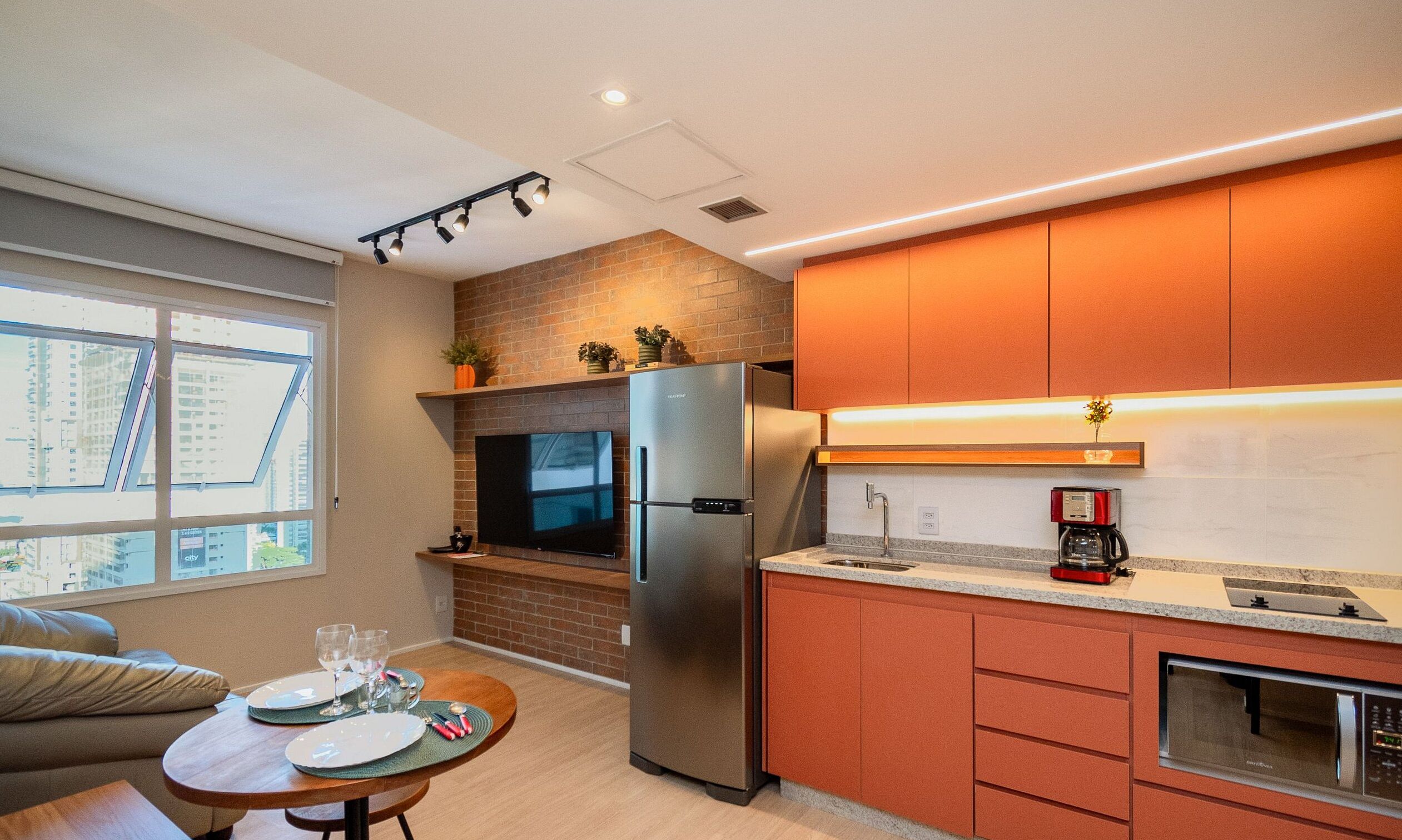 A modern kitchen with a built-in refrigerator, a TV, and a coffee maker.