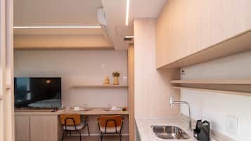 A modern kitchen with a dining area, wooden cabinets, a built-in TV, and a stainless steel sink.