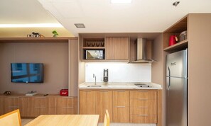 Cocina compacta con microondas, estufa y refrigerador.