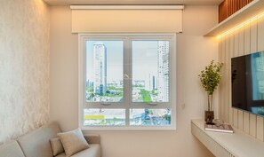 Una sala de estar moderna con un ventanal grande, un sofá, un televisor y una planta en maceta.