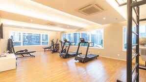 Uma academia com esteiras, aparelhos de musculação e piso de madeira.