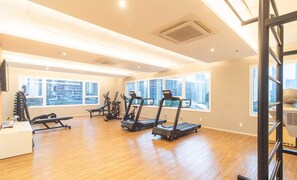Une salle de sport équipée de tapis de course, d’appareils de musculation et dotée d’un plancher en bois.